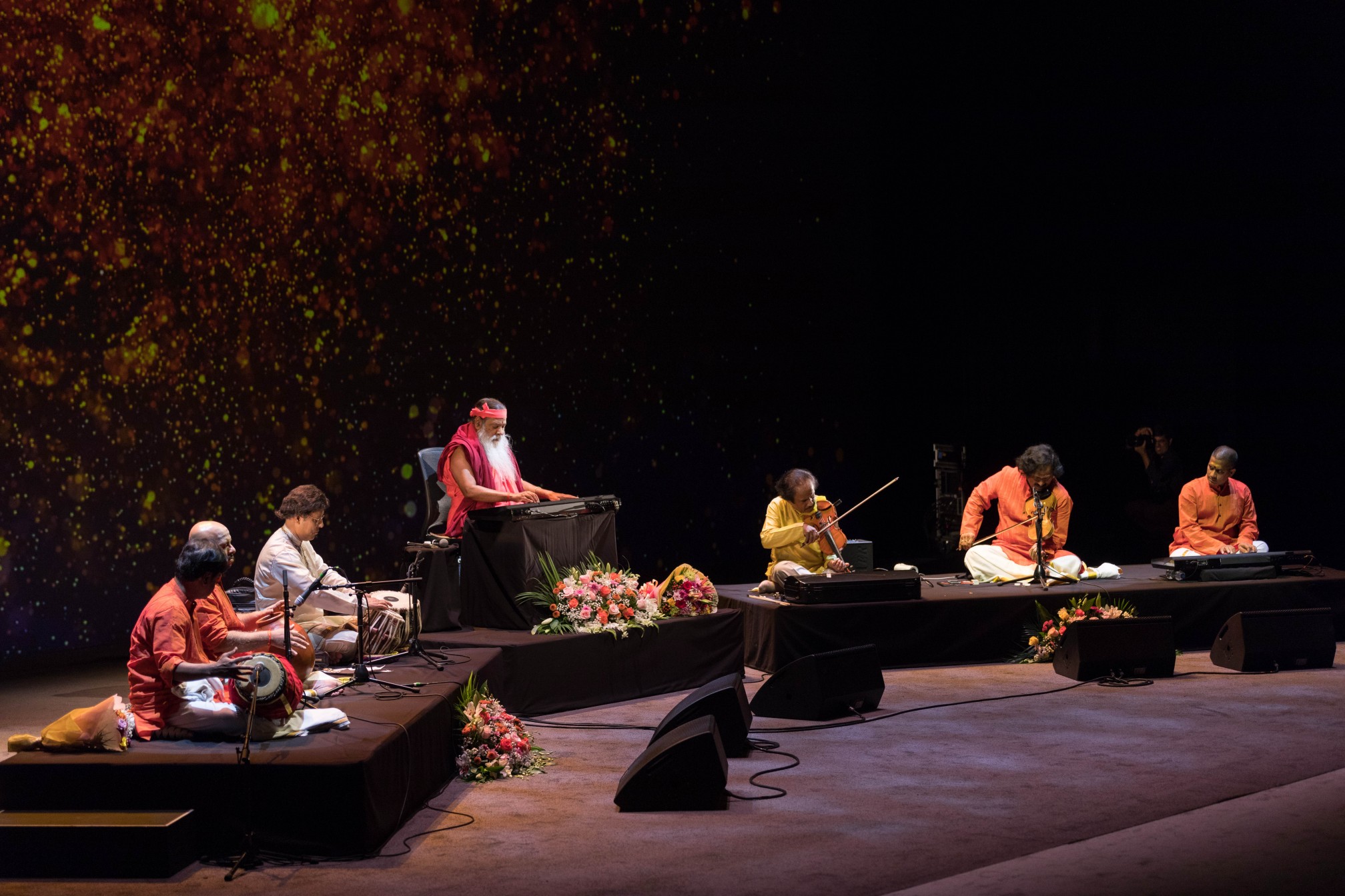 Healing Music Experience — Sri Swamiji with ensemble, amber backdrop